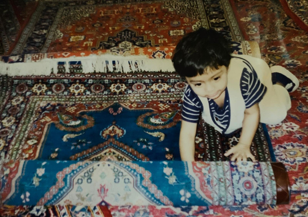A young child crawling over hand-knotted rugs at home