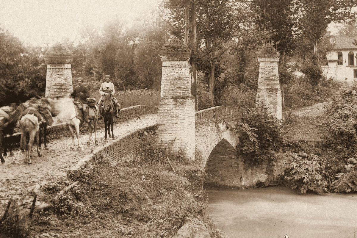 Riders and pack mules crossing a brick bridge on the road to Rasht, Persia, around 1885 to 1910