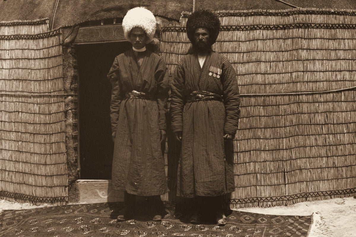 Two men standing on a knotted rug outside a yurt in Central Asia, around 1905 to 1915