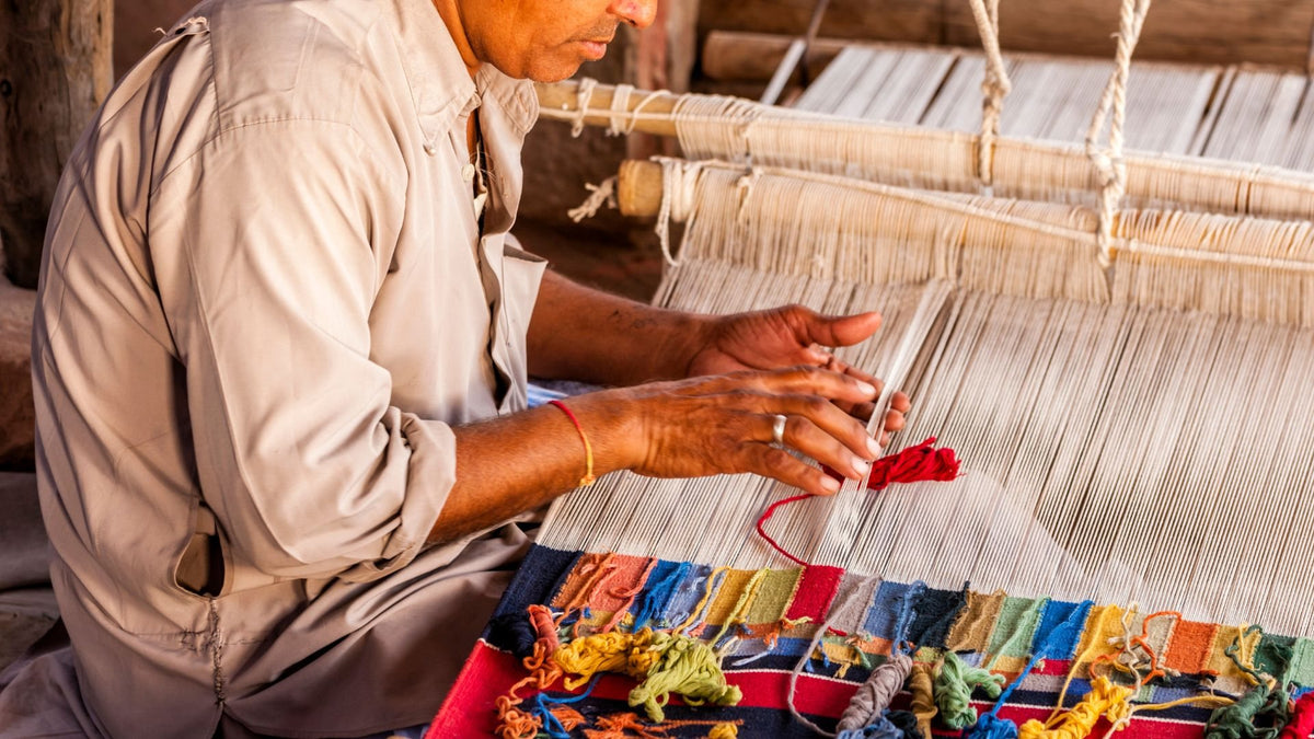 Weaver knotting a rug by hand at the loom